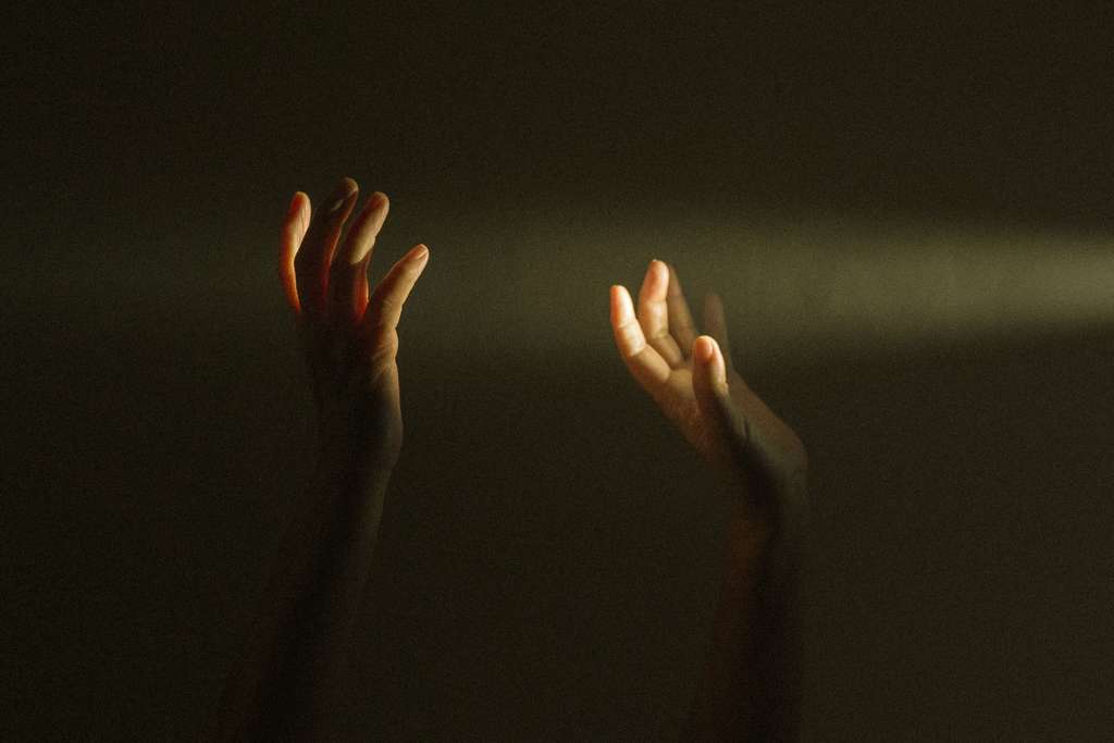 hands in darkness seeking light
